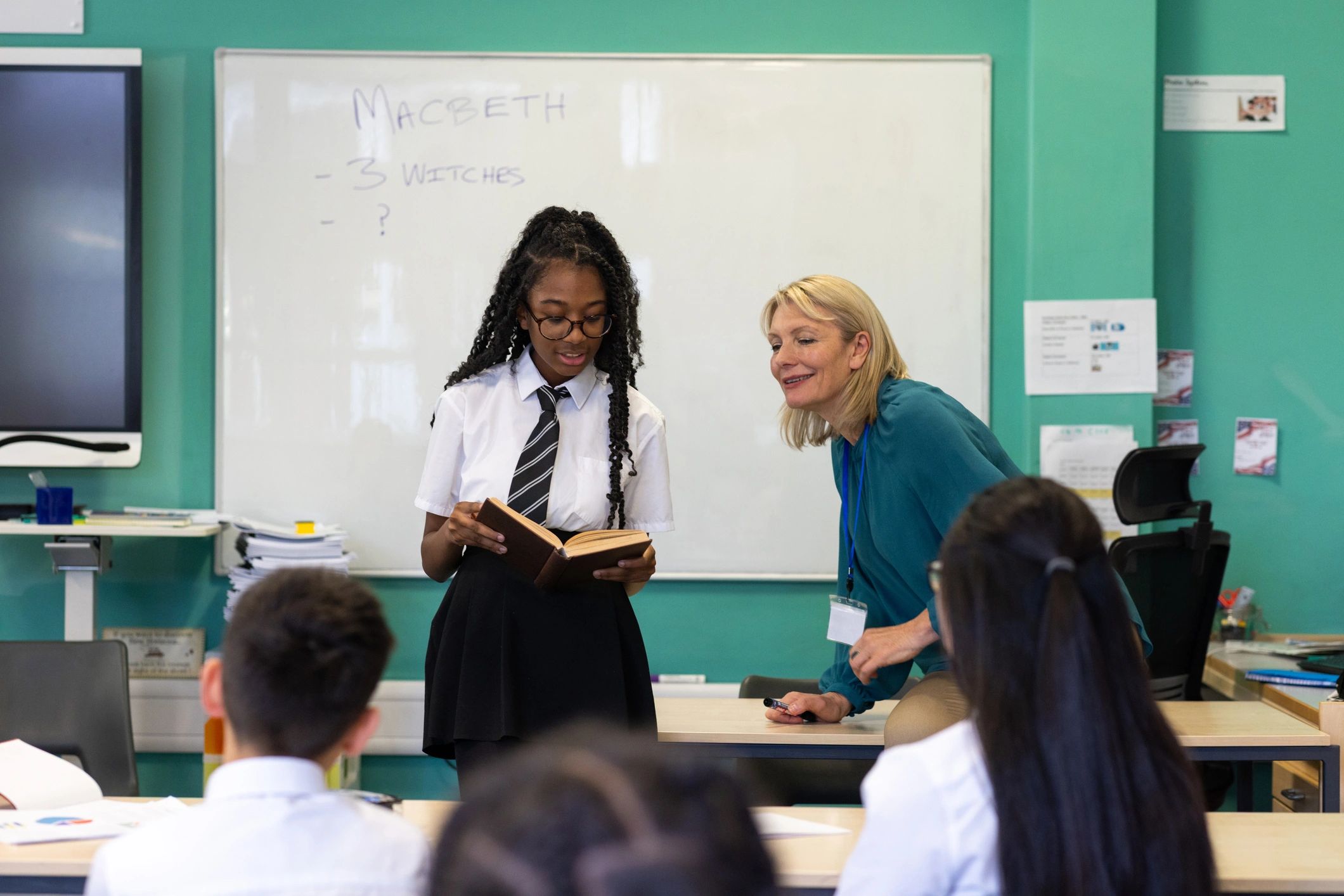 Student reading with teacher in class
